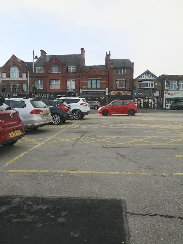 Pay & Display car park with parked cars and brick buildings in South Elmsall, Yorkshire.