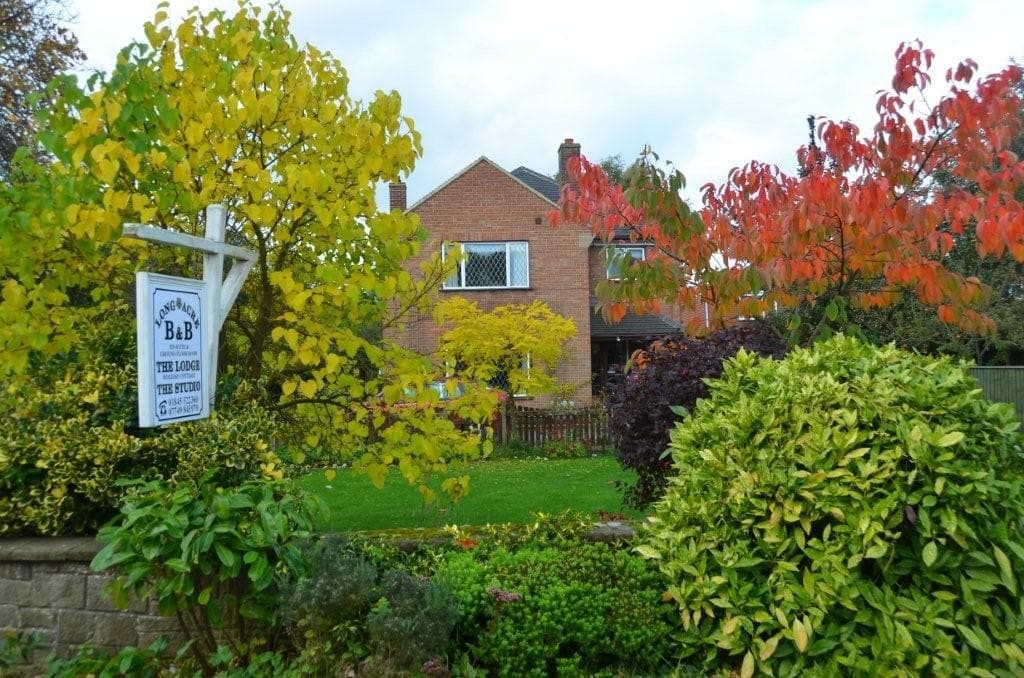 Long Acre Self-Catering Apartments surrounded by colorful autumn foliage and a lush garden in Sowerby, North Yorkshire.