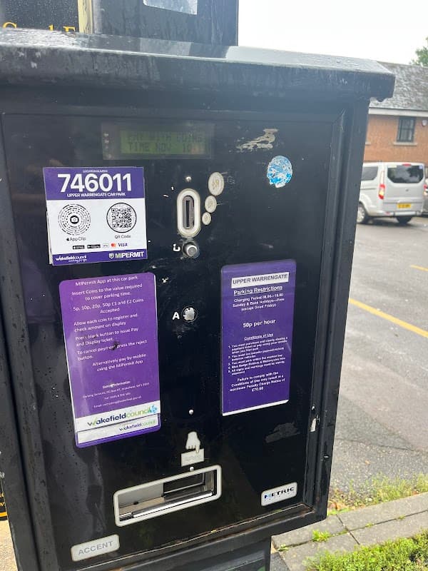 Parking meter with payment instructions and permit details, located at Upper Warrengate Car Park in Wakefield, Yorkshire.