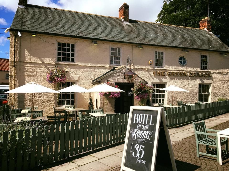 The Green Dragon pub with outdoor seating, parasols, and a sign advertising hotel rooms for £35.