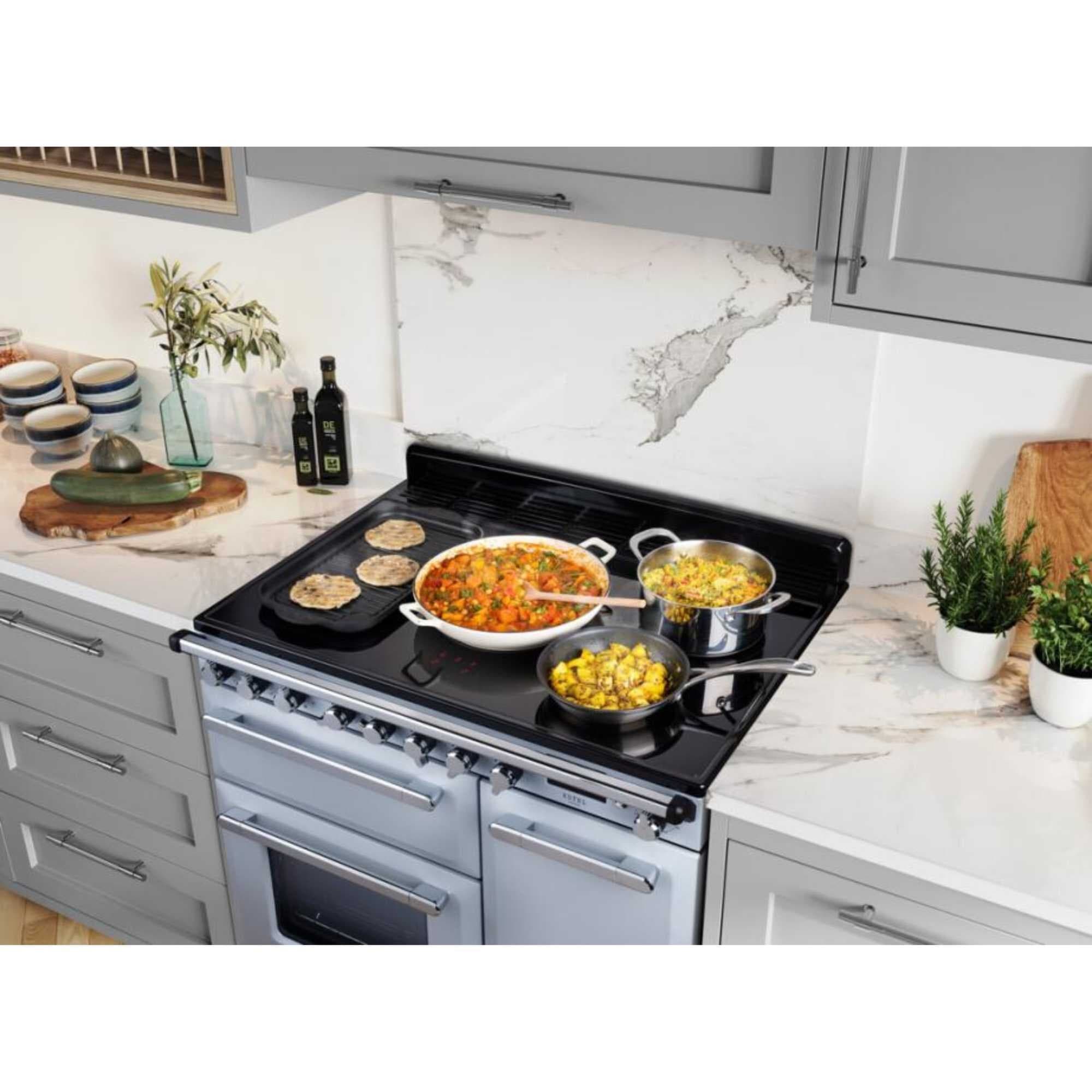 Misty blue and chrome 90cm induction range cooker with a sleek design, featuring a black cooktop, multiple cooking pots, and a stylish kitchen backdrop.