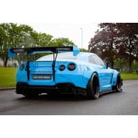 Blue Nissan GT-R with wide body kit and large rear spoiler parked on a road.
