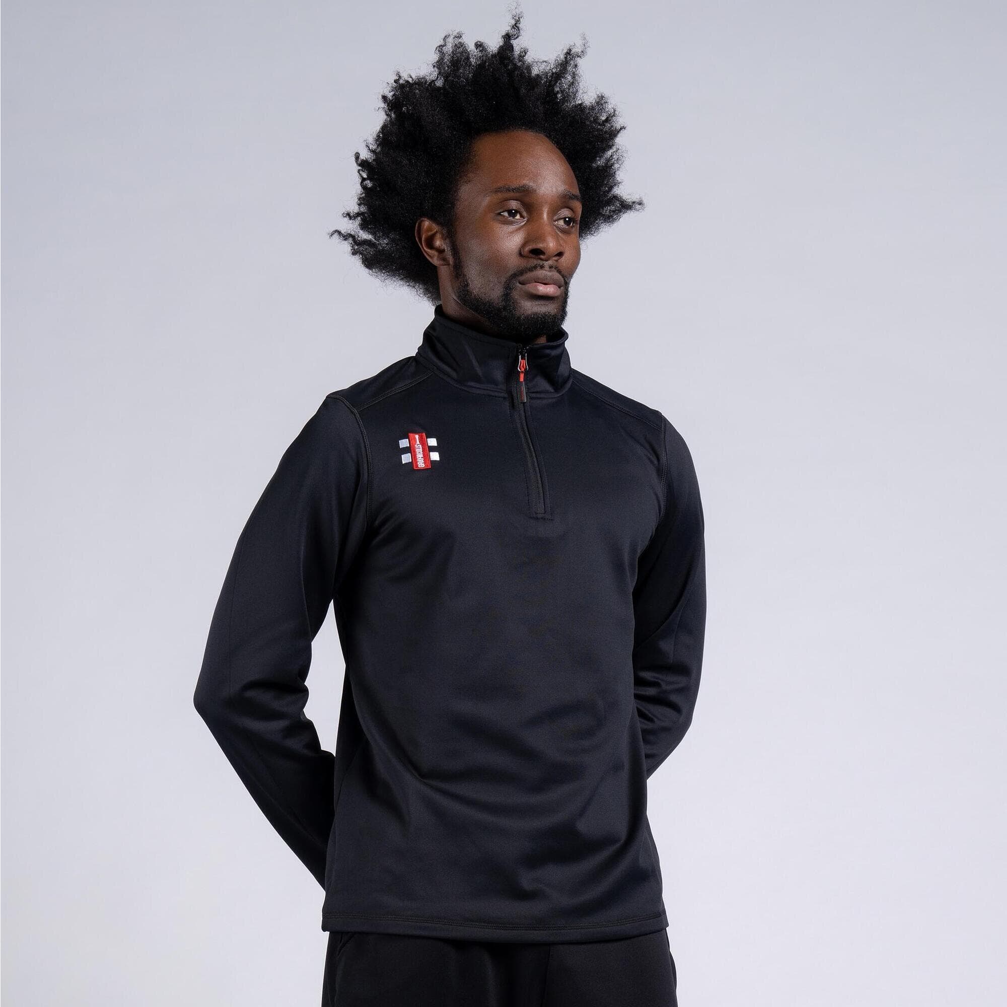 Black fleece pullover with a high collar, featuring a quarter-zip front and Gray-Nicolls logo on the chest, designed for warmth and comfort during sports activities.