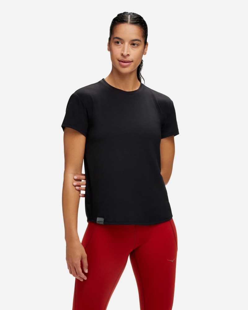 Women's HOKA Essential T-Shirt in black, made from soft material, features a classic crew neck and short sleeves, shown in size medium with a slim fit.