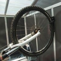 Black Palram Canopia vertical bicycle hanger holding a bike by its front wheel in a metal-framed space.