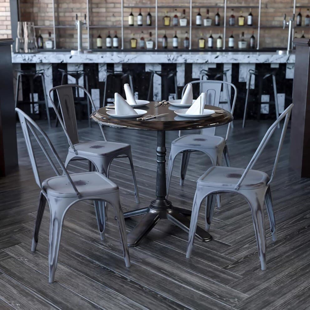 Set of 4 silver grey galvanised steel chairs with a sleek design, arranged around a round table in a stylish bar setting with a marble counter and wooden flooring.