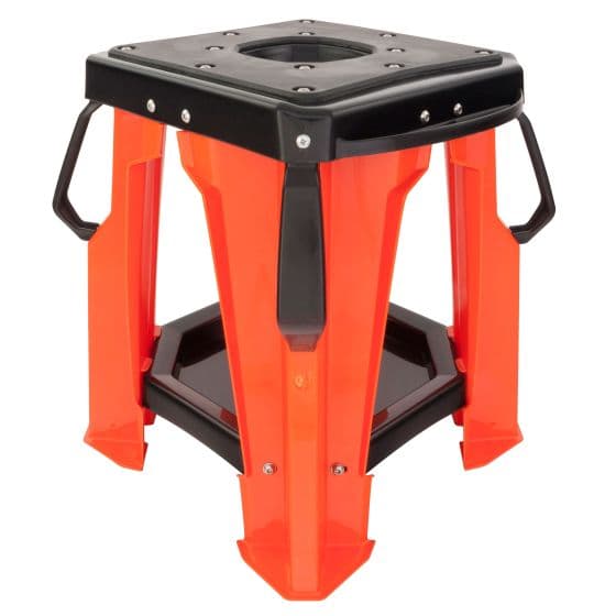 Red and black motocross bike stand with a sturdy plastic construction, featuring a square top, reinforced legs, and handles for easy transport.