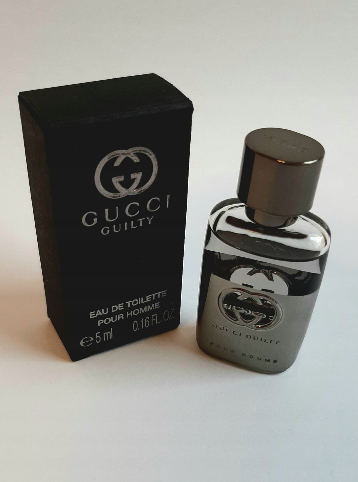Gucci Guilty Pour Homme is a 5 ml eau de toilette in a sleek glass bottle with a silver cap, featuring the iconic interlocking G logo, accompanied by a black rectangular box.