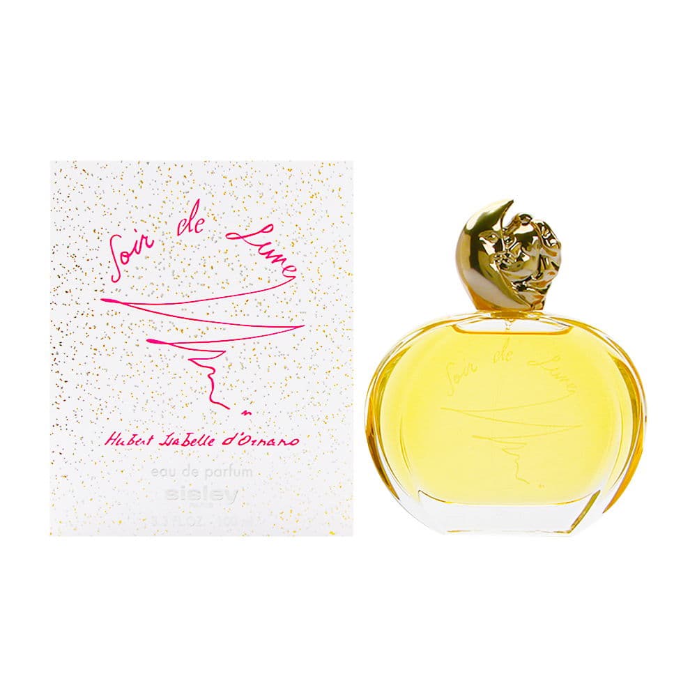 Clear glass perfume bottle with a gold crescent moon cap, filled with pale yellow fragrance, alongside a white box adorned with gold speckles and pink script.