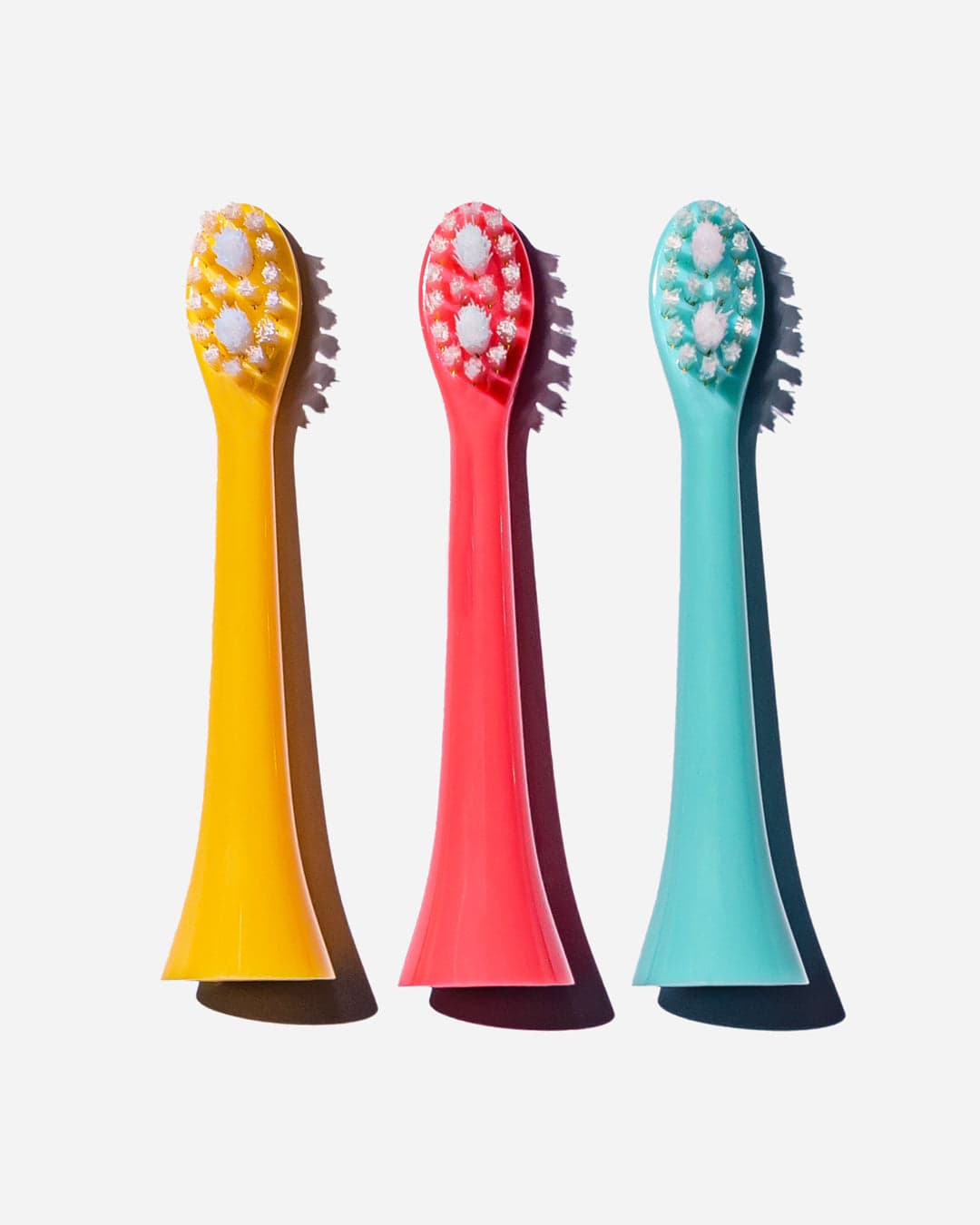 Three colorful replacement heads for children's sonic toothbrushes in yellow, red, and turquoise, featuring soft bristles and a smooth, shiny plastic material.