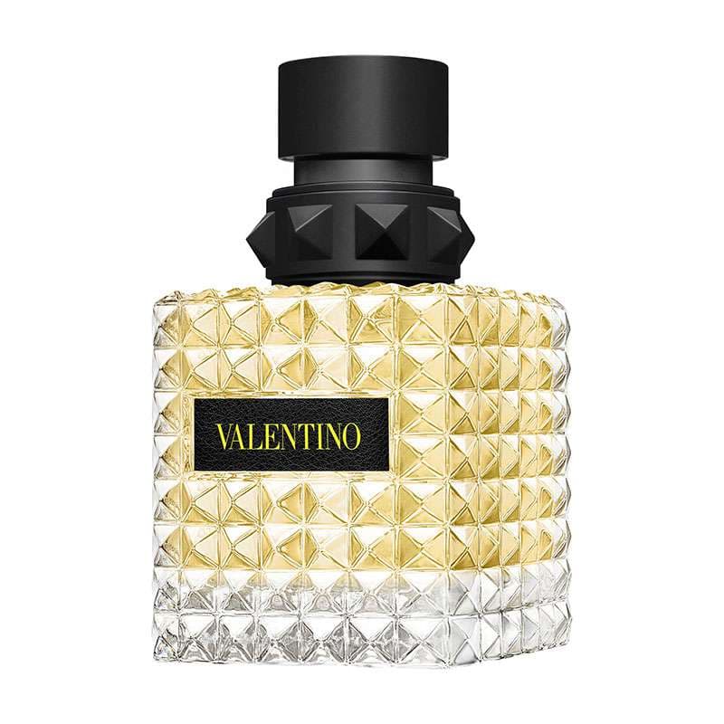 Valentino Garavani Born in Roma Yellow Dream Eau De Parfum features a textured yellow glass bottle with pyramid studs and a black cap, labeled with a black Valentino logo.