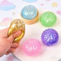 Glittery steamer bun stress ball toy in gold, pink, blue, green, and purple, with a hand squeezing the gold one.