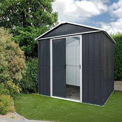 Anthracite metal shed measuring 6'8" x 4'6", featuring a sloped roof, double doors, and a sleek design, set on a grassy area with greenery in the background.