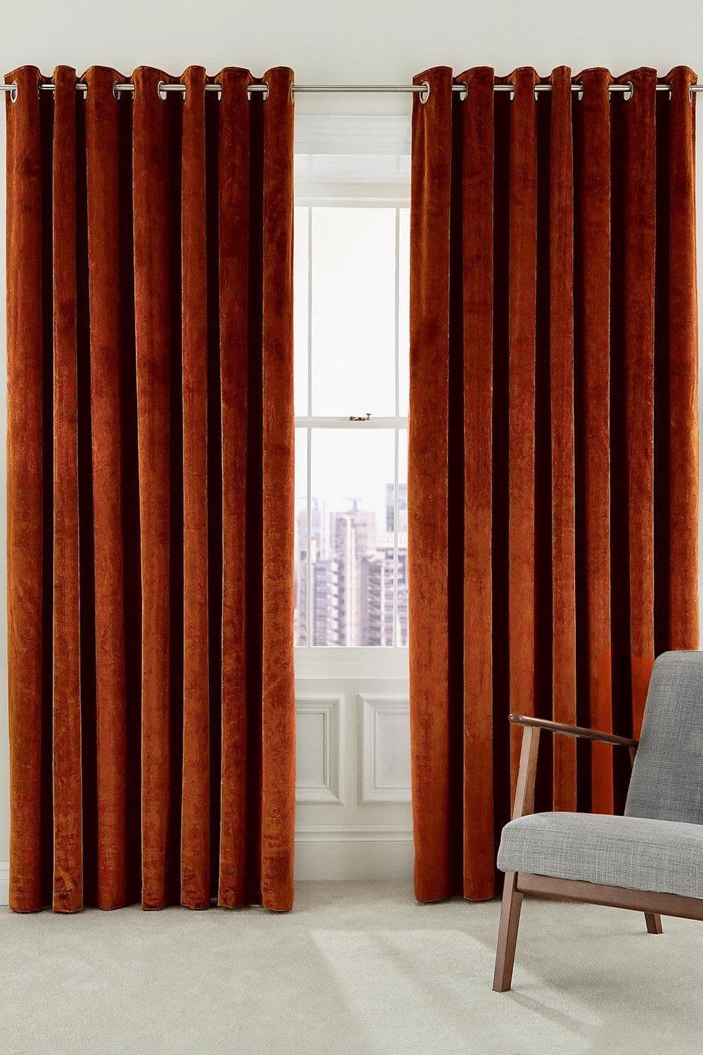 Woven lined curtains in rich copper color, featuring a luxurious texture and eyelet top, measuring 167cm width by 183cm drop, elegantly framing a window with a city view.