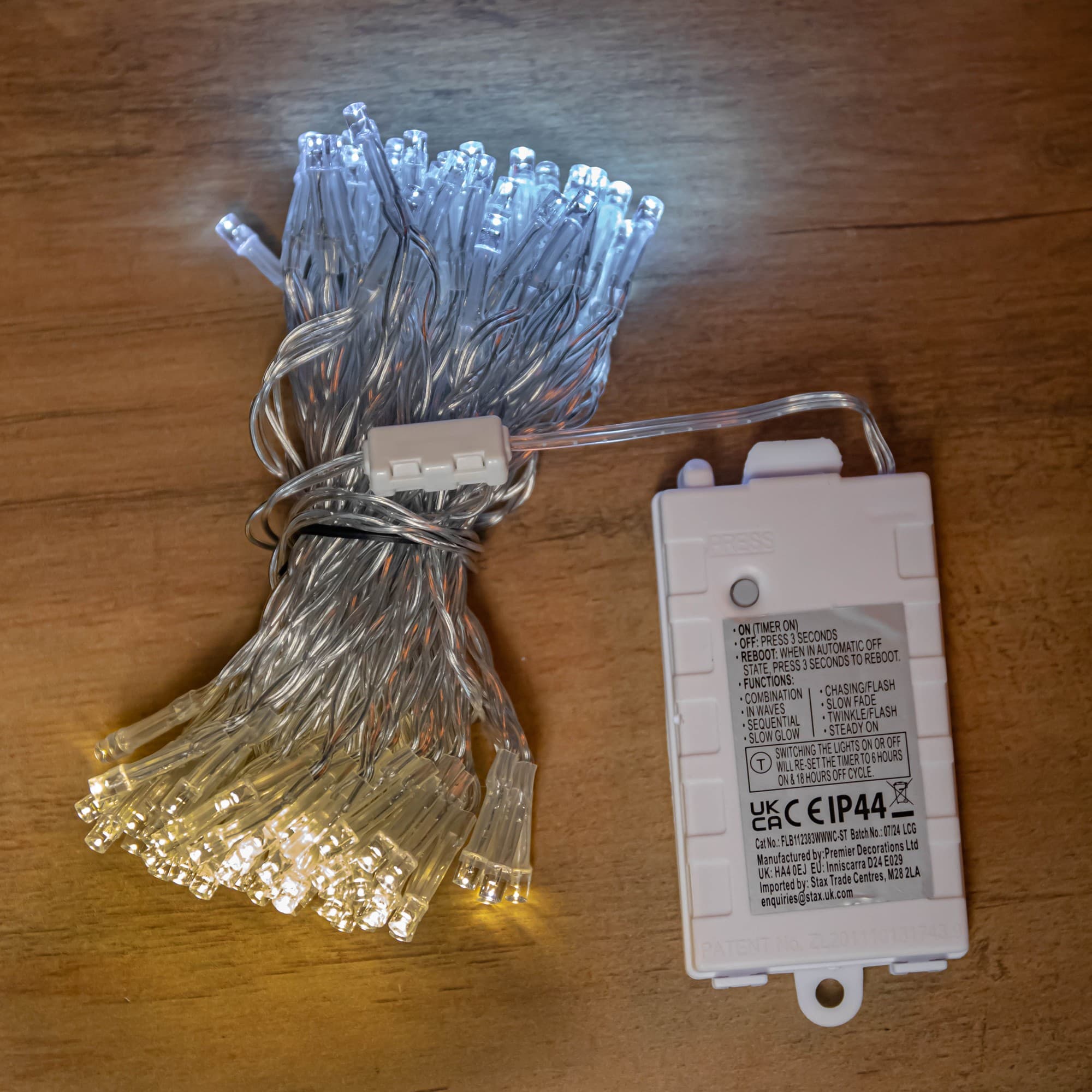10m string lights featuring 100 LED bulbs in cool and warm white, with a clear plastic casing and a battery-operated control box for versatile holiday decorating.