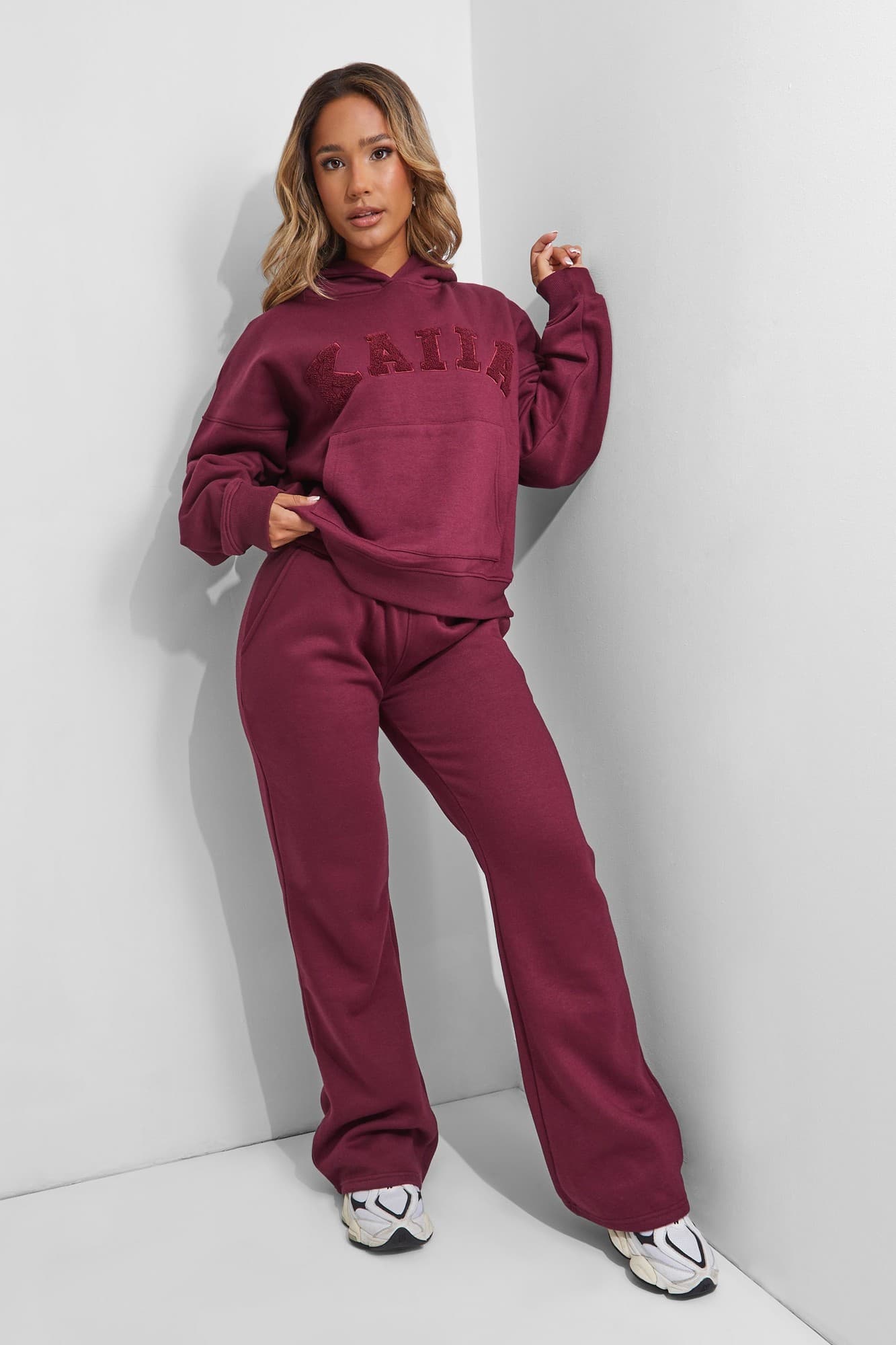 Deep burgundy wide leg sweatpants made of soft material, featuring an elastic waistband and a relaxed fit, paired with a matching hoodie displaying the "Kaiia" logo.