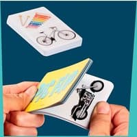 Mattel Games Pic Flip Card Game with colorful images, including a bicycle and musical instruments, held in hands.