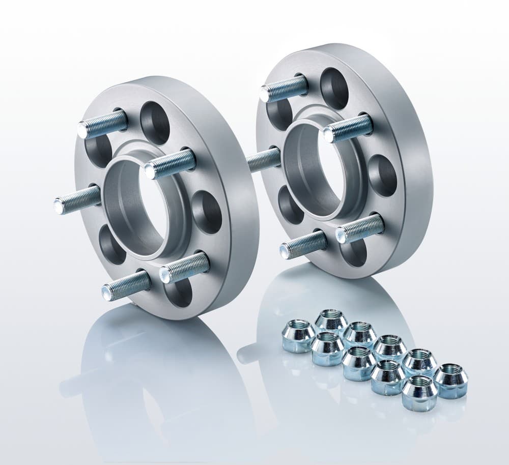 Silver aluminum track widening spacers with five holes each, featuring protruding bolts, accompanied by a set of chrome wheel nuts.