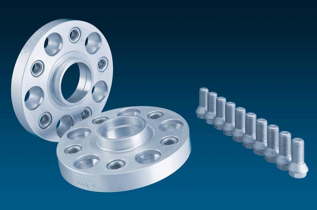 Silver aluminum H&R 7055665 TRAK+® wheel spacers, 35mm thick, featuring five holes, with accompanying silver bolts, set against a dark blue background.
