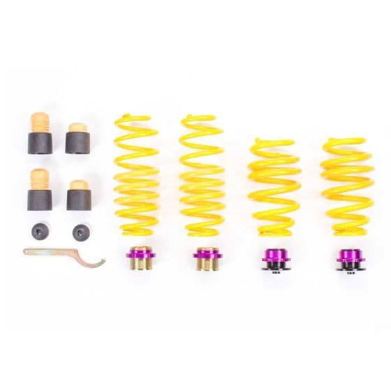 Yellow coil springs with purple and gold accents, accompanied by mounting hardware including spacers and a tool, designed for adjustable lowering of vehicle height.