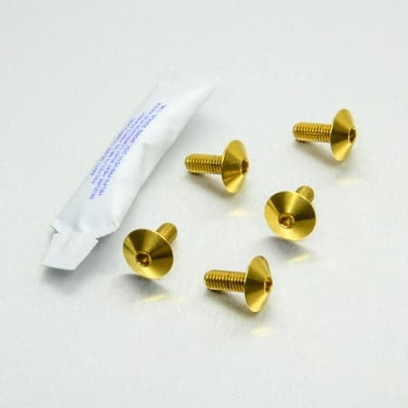Pro-Bolt Stainless Steel Chain Guard Bolt Kit featuring five gold bolts with a flat, rounded head and a small hex socket, accompanied by a packet of thread-locking adhesive.