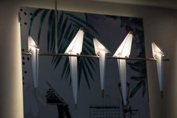 Modern hotel room with a plush bed, elegant lighting, and a side table adorned with a vibrant bouquet of flowers.