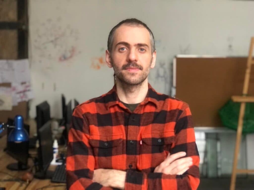 Person in red plaid shirt standing in art studio