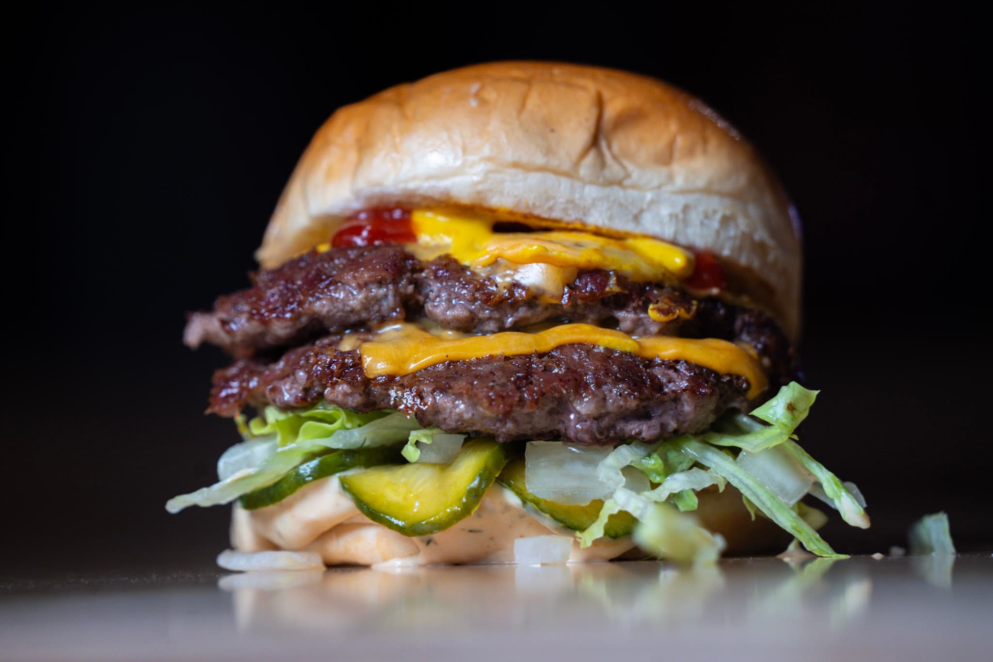 Close-up of a double cheeseburger with lettuce and pickles