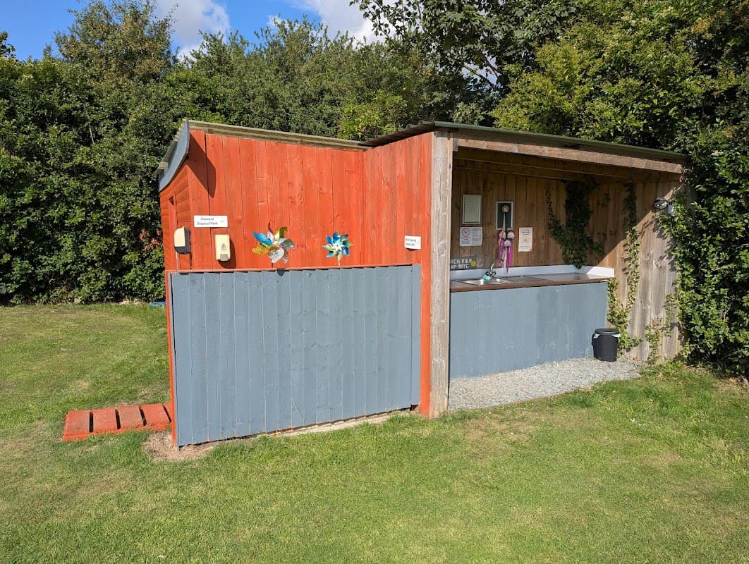 Colorful wooden structure with blue and red walls, surrounded by greenery, featuring outdoor facilities and decorations.