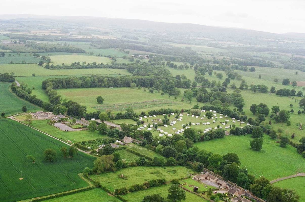 Aerial view of Constable Burton Hall Caravan Park, surrounded by lush green fields and trees in North Yorkshire.