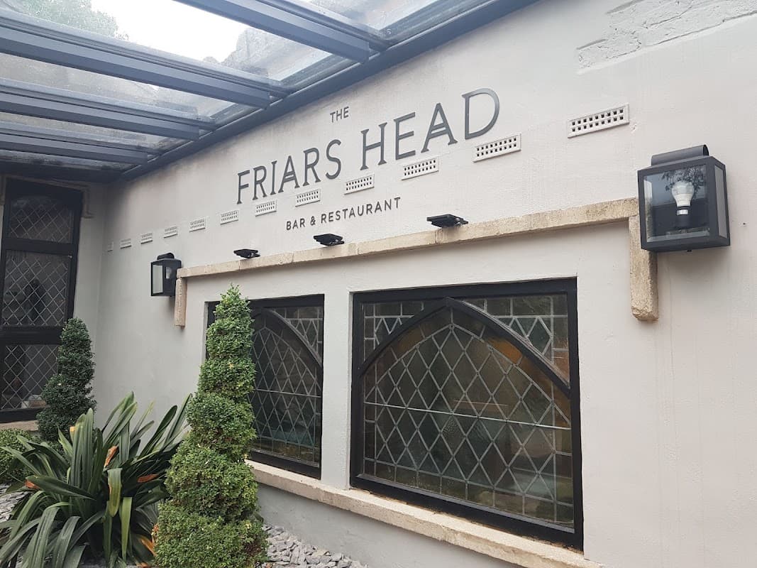 Signage for "The Friars Head" bar and restaurant, with decorative plants and stone accents.