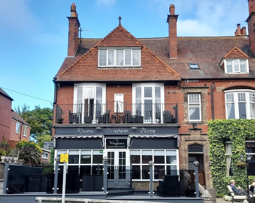 Victorian-style building with a balcony, featuring "Wayfarer" signage and outdoor seating in a quaint Yorkshire setting.