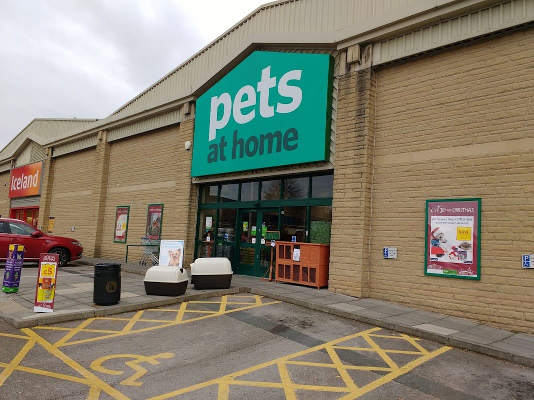 Entrance to Pets at Home shop with green signage, outdoor seating, and promotional posters in Halifax, Yorkshire.