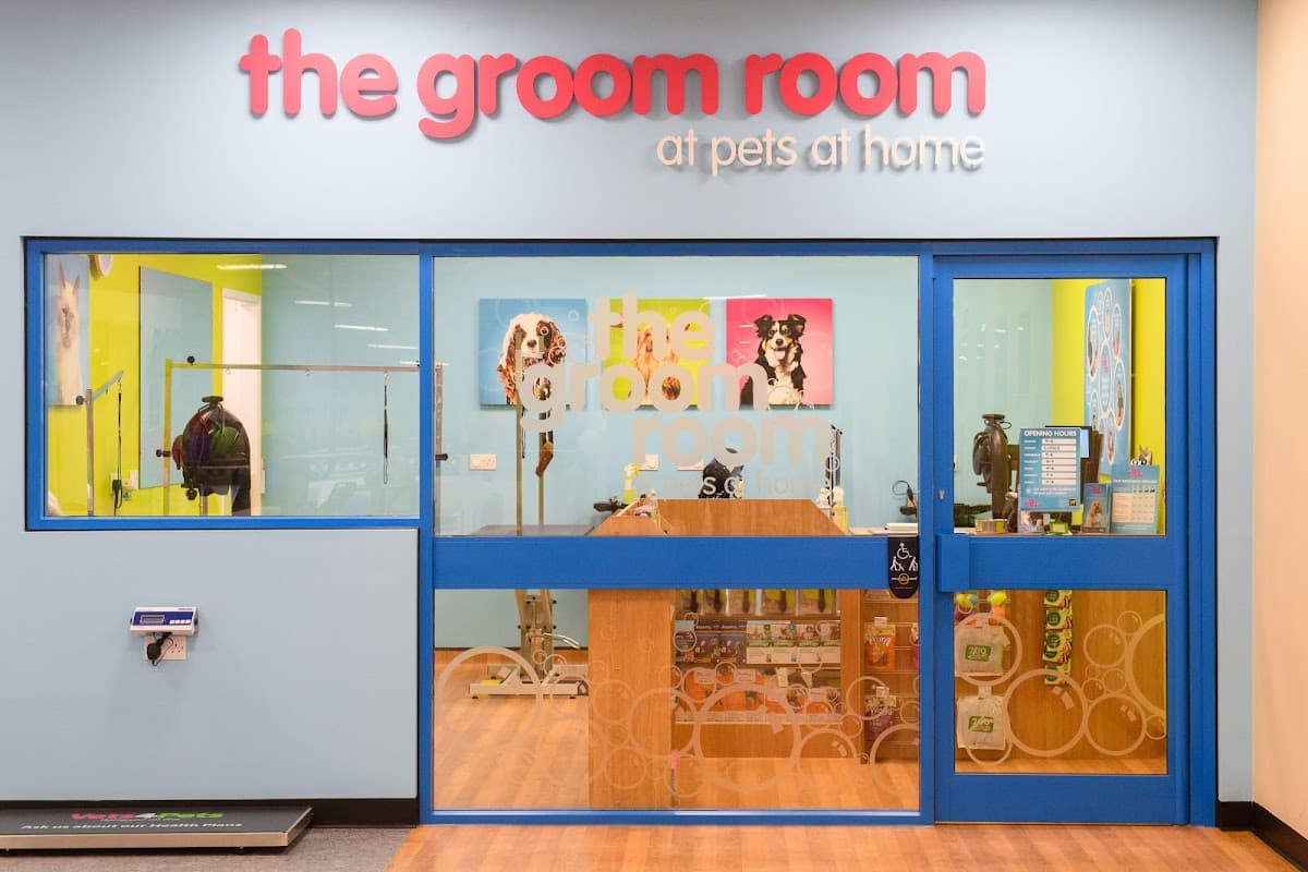 Brightly colored storefront of The Groom Room, featuring a large sign and glass entrance with pet grooming supplies visible inside.