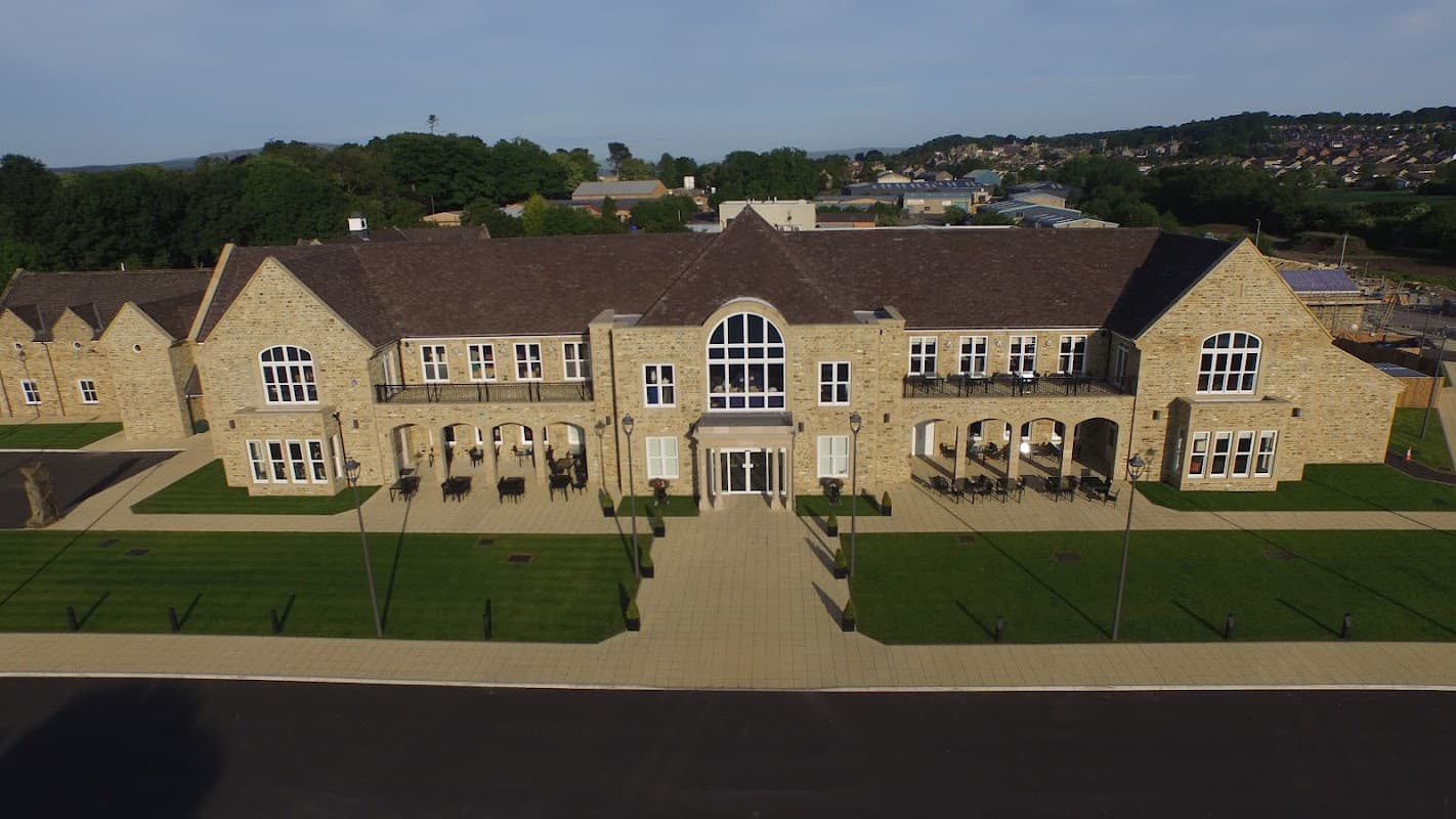 Stone building with large windows, manicured lawns, and outdoor seating in a scenic Yorkshire landscape.