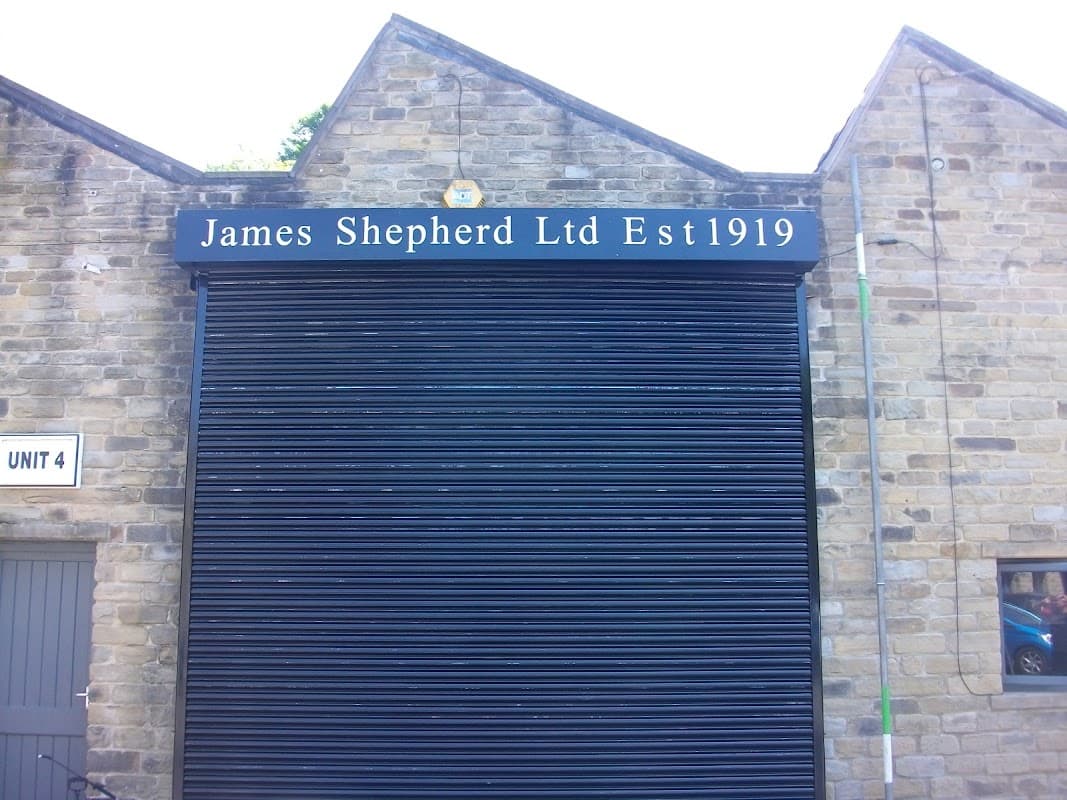 Black roller shutter with "James Shepherd Ltd Est1919" sign on a stone building in Hebden Bridge, Yorkshire.