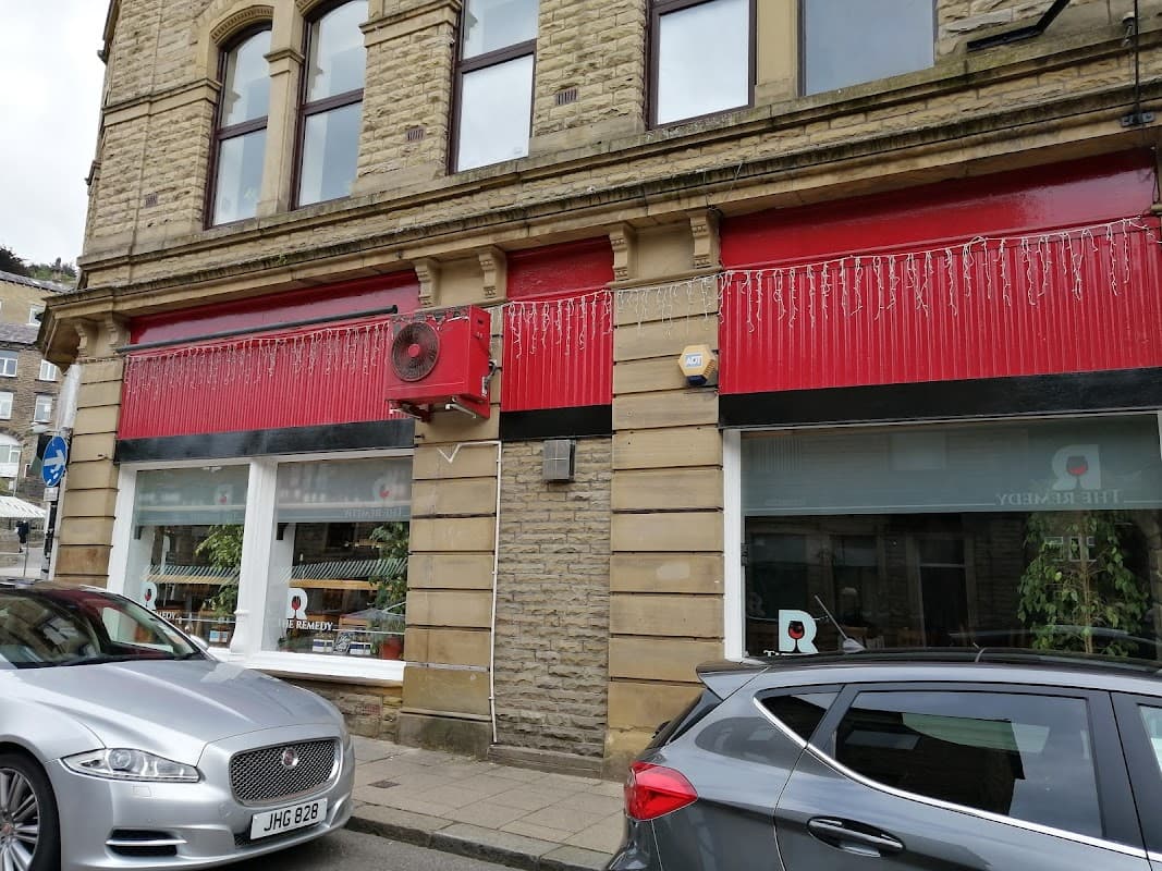 Red and stone faΓ§ade of The Remedy Wine Merchants shop, featuring large windows and decorative elements.