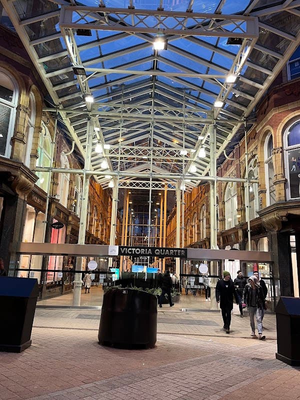 Victoria Quarter in Leeds, featuring a glass roof, modern architecture, and people walking through the shopping arcade.