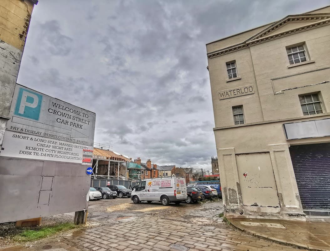 Crown Street Car Park sign, cloudy sky, parked vehicles, and nearby buildings in Leeds, Yorkshire.