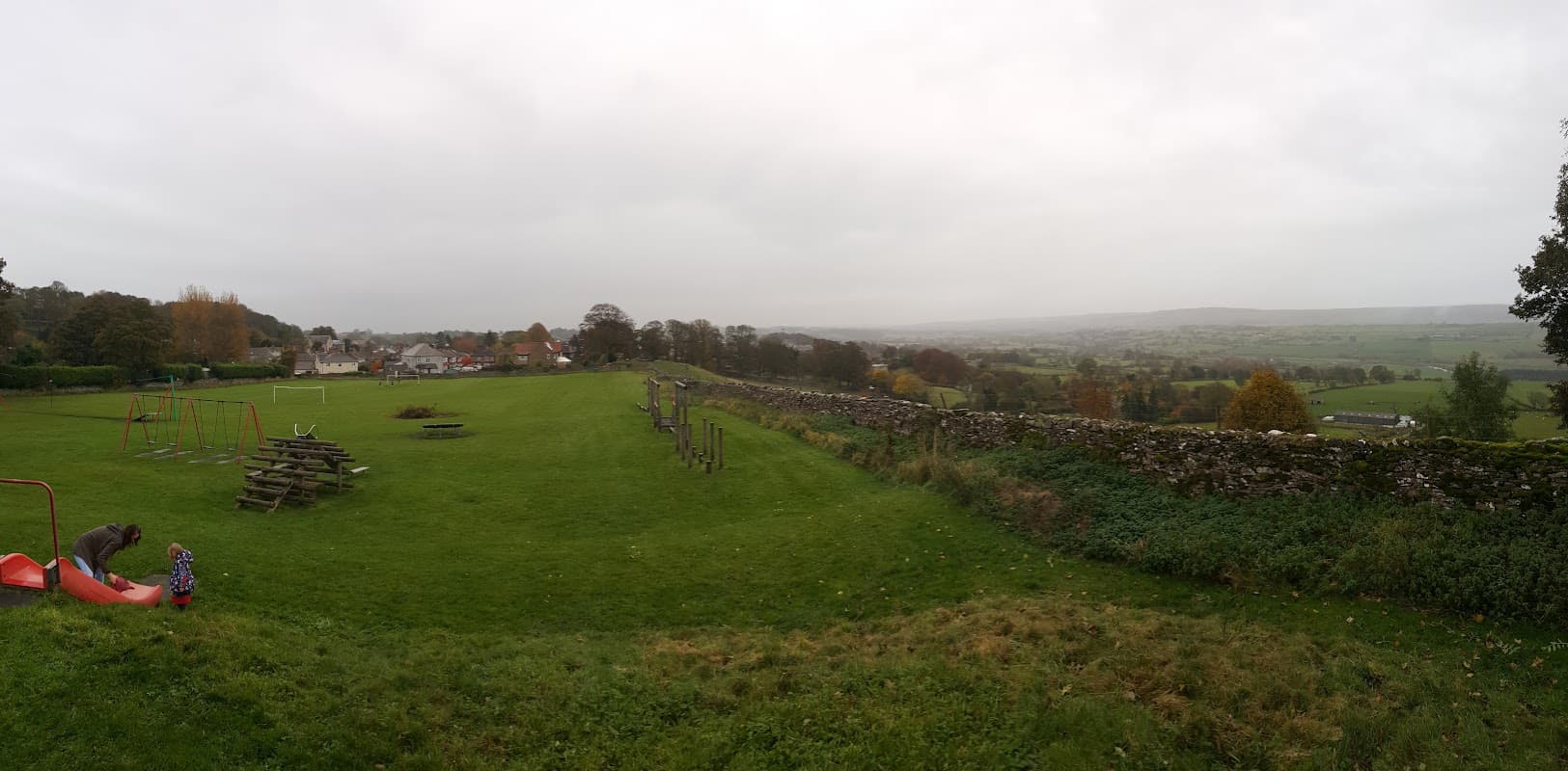 Leyburn Playground features swings, climbing structures, and grassy areas with a scenic view of the surrounding countryside.