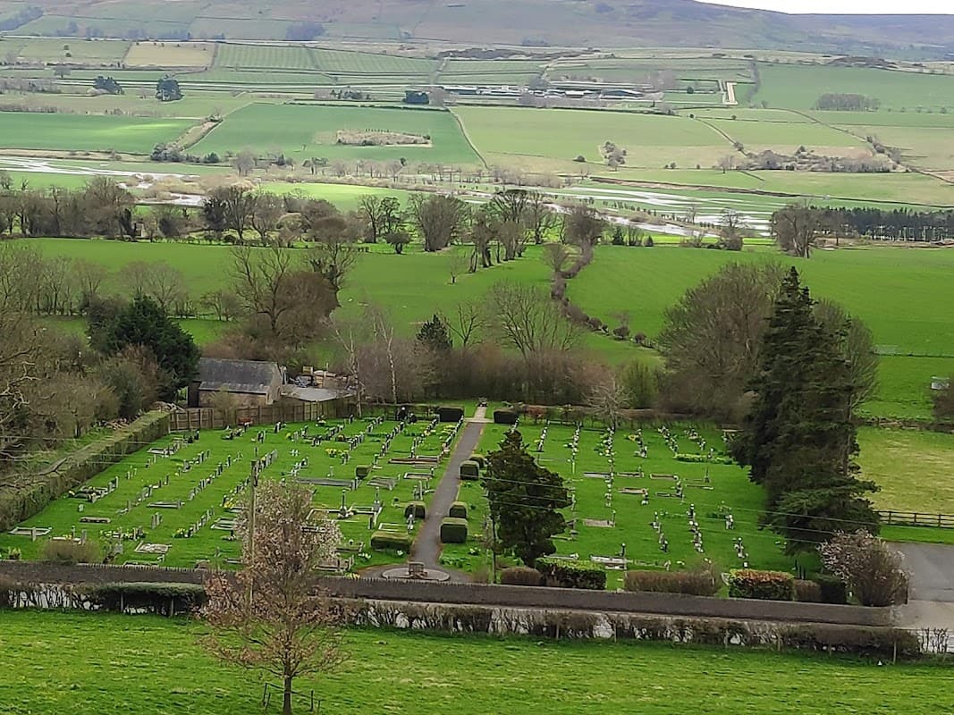 Aerial view of a cemetery surrounded by lush green fields and rolling hills in Leyburn, Yorkshire.