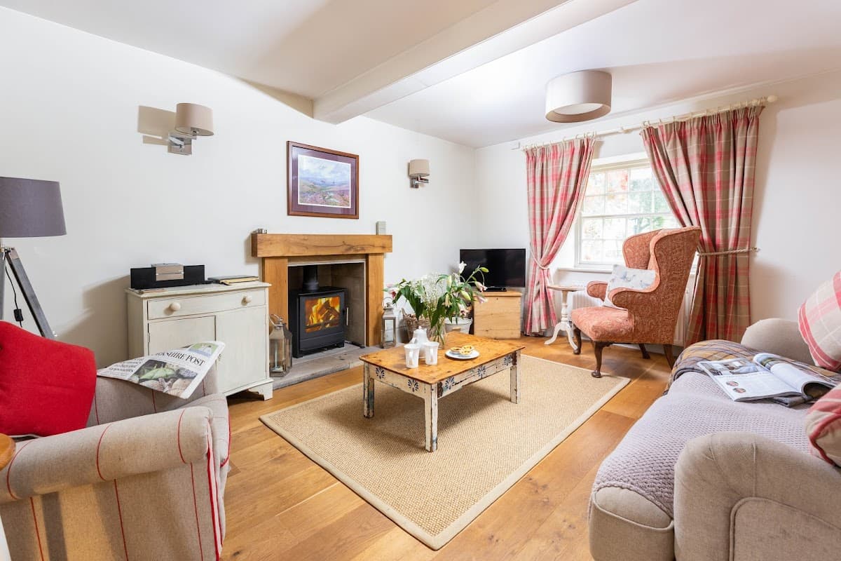 Cozy living room with a fireplace, comfortable seating, and warm decor in Habton House Farm Holiday Cottages.