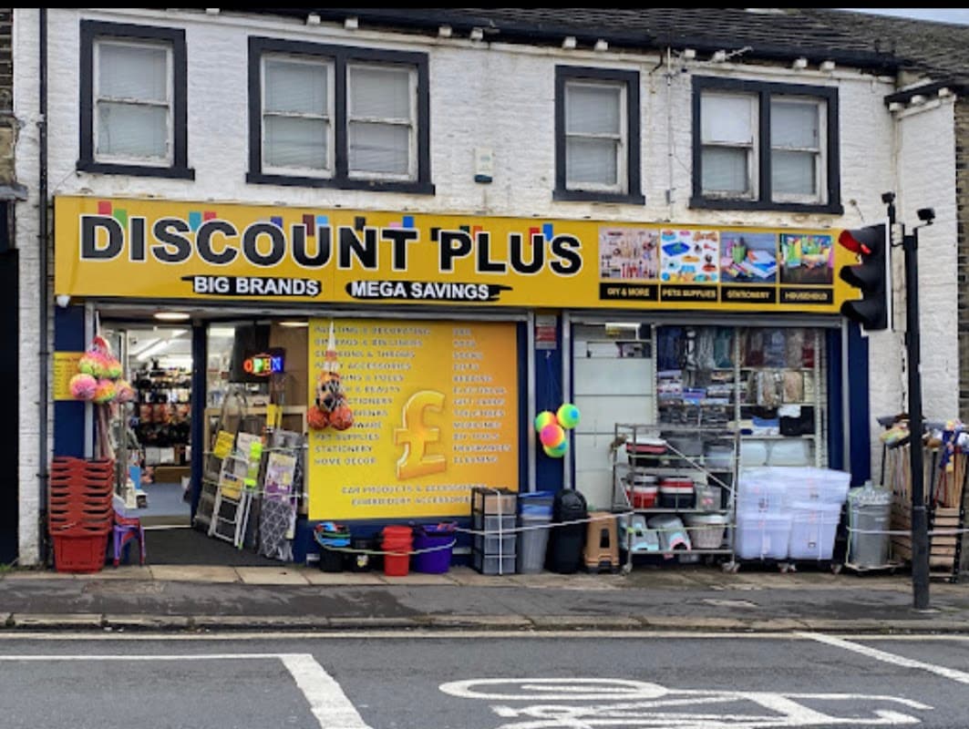 Bright storefront of Discount Plus featuring pet supplies, colorful signage, and various items displayed outside.
