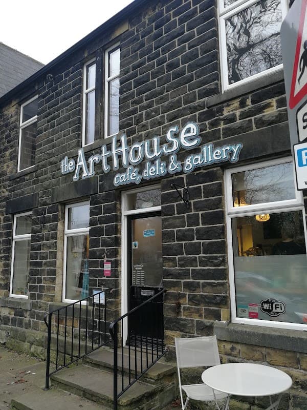 The ArtHouse Cafe features a stone facade with large windows and a sign displaying its name, cafe, deli, and gallery.