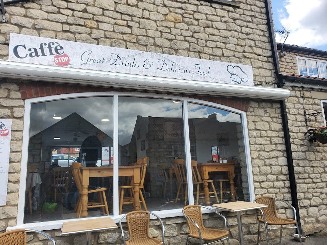 Caffé Stop Pickering features a stone exterior, large windows, wooden tables, and outdoor seating.
