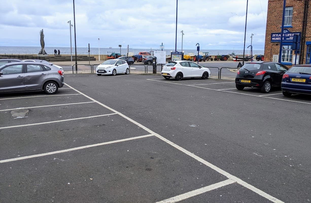 Pay & Display car park with parked cars, sea view, and nearby buildings in Redcar and Cleveland, Yorkshire.