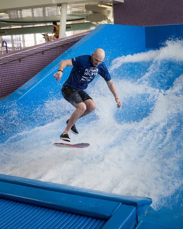 A man surfing on a flowboard in a wave pool at Redcar Leisure Centre, surrounded by splashing water.