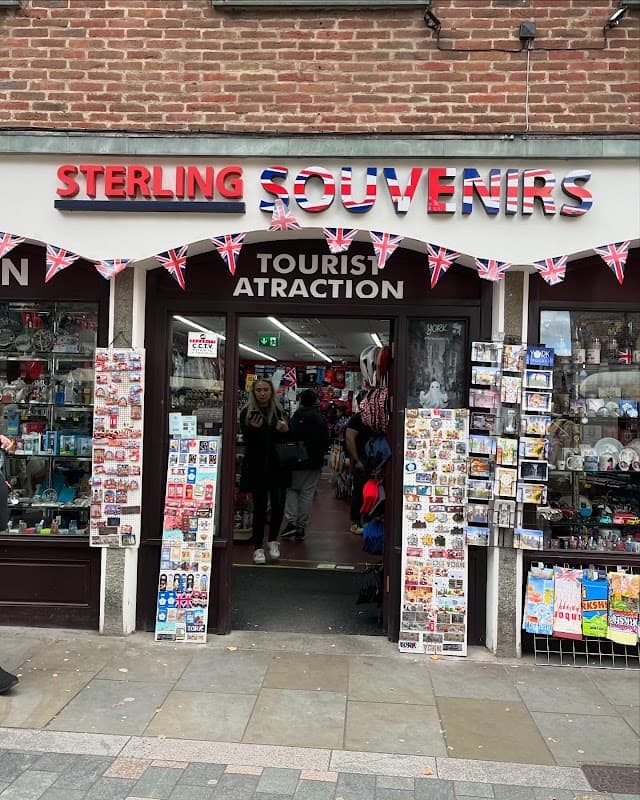 Quaint storefront with "Sterling Souvenirs" sign, British flags, and various souvenirs displayed in windows.