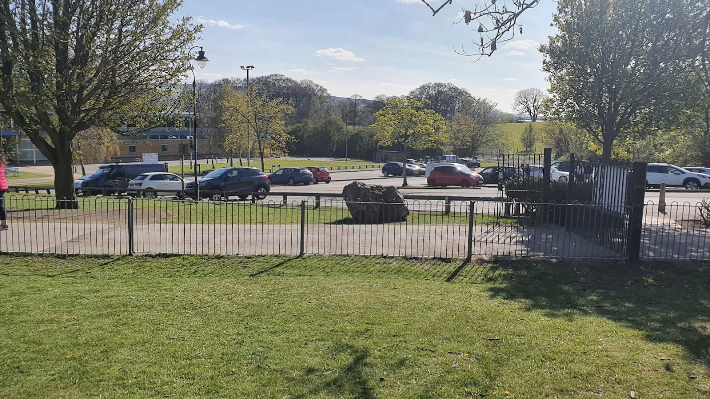 Pay & Display car park at Aireville Park, with parked cars, green grass, and trees in a sunny Yorkshire landscape.