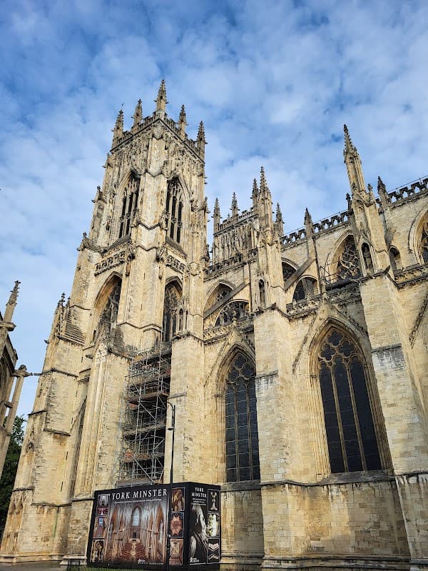 York Minster's towering gothic architecture, scaffolding on one side, under a partly cloudy sky.